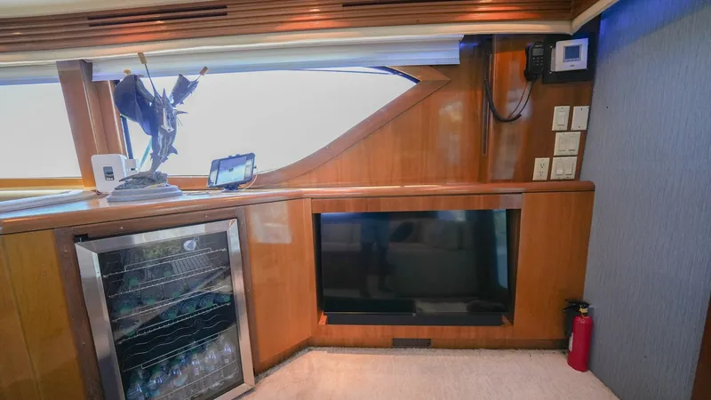 Slide: The Image of Salon Entertainment Center and Bar Area The salon of the Hatteras 60 Convertible features a sophisticated entertainment center with a sleek flat-screen TV and built-in bar amenities. The fine wood cabinetry complements the luxurious ambiance, while ample natural light pours in through large win - 8734330