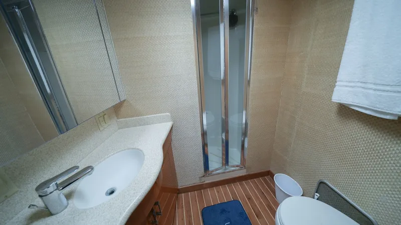 Slide: The Image of En-Suite Bathroom with Shower This well-appointed en-suite bathroom features a sleek vanity with a modern sink and a mirrored cabinet for ample storage. The space is elegantly finished with warm wood flooring and textured wall coverings, creating a luxurious atmosphere. A compact show - 8734334
