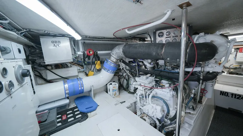 Slide: The Image of Engine Room with Twin Engines This well-maintained engine room of the 2001 Hatteras 60 Convertible, Uno Mas, features dual powerful engines, ensuring optimal performance. The space is well-lit and organized, with easy access to essential components and systems. Notable features includ - 8734345