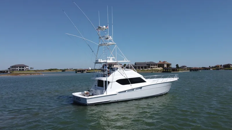 Slide: The Image of Starboard View of Hatteras 60 Convertible This image showcases the sleek profile of the 2001 Hatteras 60 Convertible, highlighting its robust sportfishing tower and expansive flybridge. The vessel's elegant lines are complemented by the crisp white hull and spacious cockpit, designed for both fis - 8734379