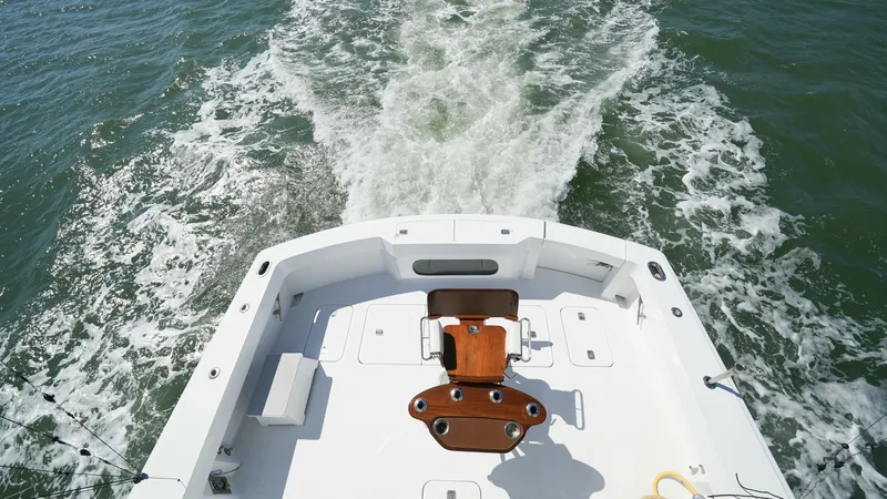 Slide: The Image of Aft Deck with Fishing Chair The aft deck of the 2001 Hatteras 60 Convertible features a spacious fishing area equipped with a robust fighting chair. The clean, expansive deck provides ample room for maneuvering during fishing excursions, while the surrounding coaming bolsters offer - 8734356