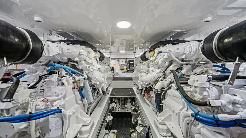 Slide: The Image of Engine Room with Twin Engines The engine room of the 2021 Viking 54 Convertible, 'Pipe Dream', showcases powerful twin engines meticulously organized within a spacious layout. The pristine white surfaces and advanced engineering components highlight the vessel's superior craftsmanship - 8673340