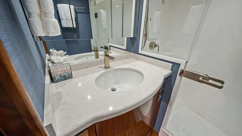 Slide: The Image of Elegant Ensuite Bathroom This stylish ensuite bathroom on the 2021 Viking 54 Convertible features a sleek white countertop and a modern faucet. The space is complemented by a spacious mirrored cabinet and elegant wood finishes, providing both functionality and luxury. The enclose - 8673307
