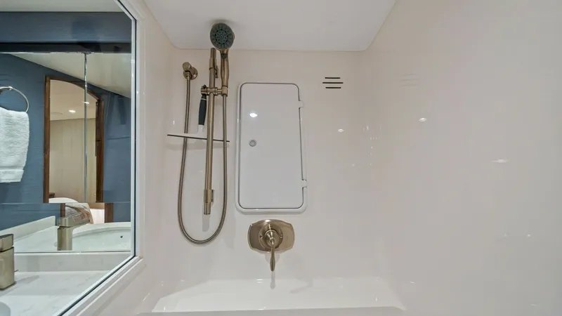 Slide: The Image of Enclosed Shower with Modern Fixtures This image showcases the enclosed shower area aboard the 2021 Viking 54 Convertible, 'Pipe Dream'. The shower features sleek, modern fixtures including a handheld showerhead and built-in shelving for convenience. The design is both elegant and functional, - 8673309