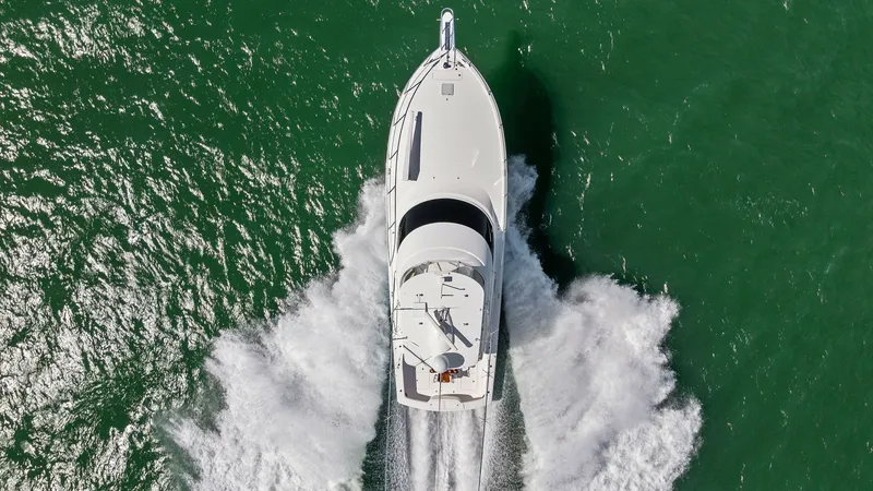 Slide: The Image of Aerial View of Yacht in Motion This aerial shot captures the Viking 54 Convertible 'Pipe Dream' cutting through the water with impressive speed and elegance. The sleek design and powerful performance are highlighted by the dynamic wake trailing behind. The vessel's streamlined profile - 8673358
