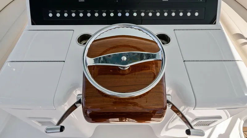 Slide: The Image of Helm Station with Electronics Displays The helm station of the 2021 Viking 54 Convertible, 'Pipe Dream', features a sleek, polished wood steering wheel and dual throttle controls. The modern electronics displays provide comprehensive navigation and vessel information at a glance. This ergonomi - 8673321