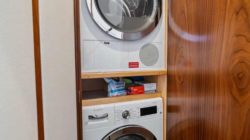 Slide: The Image of Laundry Station in Companionway Closet This image showcases the convenient laundry station aboard the Viking 54 Convertible, featuring a stacked Bosch washer and dryer set. Nestled within a sleek wooden cabinet, this space maximizes utility without compromising on style. Ideal for long voyages - 8673310
