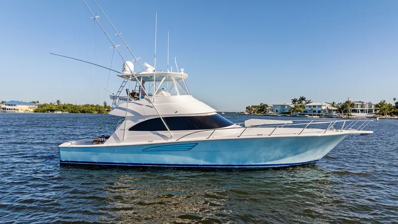 Slide: The Image of Starboard Profile of Viking 54 Convertible This image captures the sleek starboard profile of the 2021 Viking 54 Convertible, Pipe Dream. The vessel boasts a streamlined hull with a striking blue finish, complemented by a spacious flybridge and advanced sportfishing equipment. Its modern lines and - 8673349