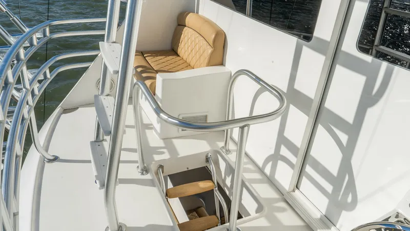 Slide: The Image of Flybridge Access with Seating This image captures the flybridge access of the 2019 Viking 68 Enclosed Bridge, featuring a secure stairway and comfortable seating. The area is designed with sleek stainless steel railings and a plush bench, offering both safety and relaxation. The open - 8738050