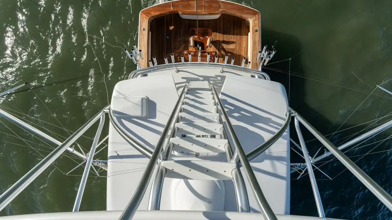 Slide: The Image of Aerial View of Aft Deck and Tower This striking aerial shot captures the aft deck of the 2019 Viking 68 Enclosed Bridge, showcasing its elegant wooden finish and spacious layout. The sleek ladder leads up to the enclosed bridge, highlighting the vessel's sophisticated design and robust st - 8738066