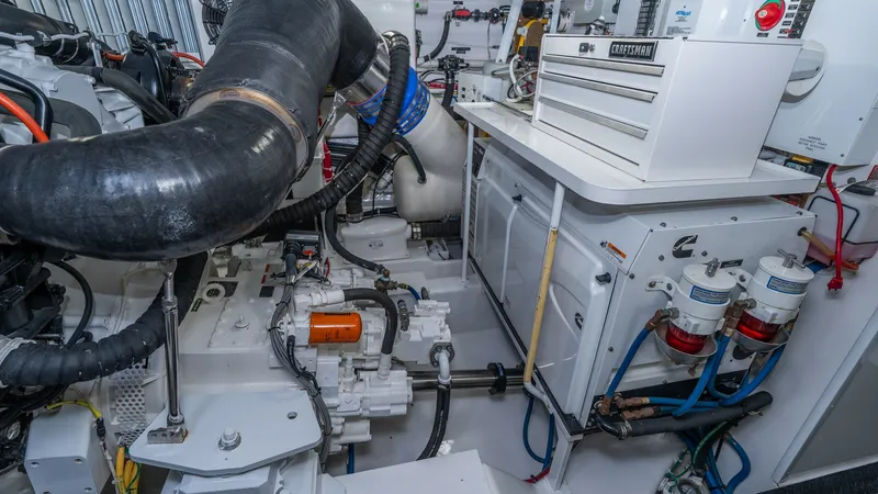 Slide: The Image of Engine Room with Tool Storage The engine room of the 2019 Viking 68 Enclosed Bridge is meticulously organized, featuring advanced machinery and systems. A prominent Craftsman tool chest sits on a sturdy work surface, providing easy access to essential maintenance tools. The space is w - 8738082