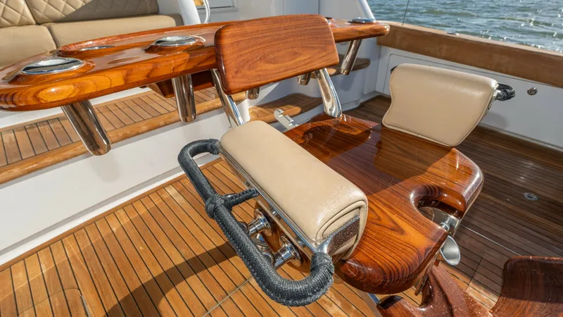 Slide: The Image of Teak Cockpit with Fighting Chair This image showcases the exquisite teak cockpit of the 2019 Viking 68 Enclosed Bridge, featuring a premium fighting chair. The chair is crafted with polished wood and cushioned seats, designed for comfort and functionality during fishing excursions. The s - 8738057