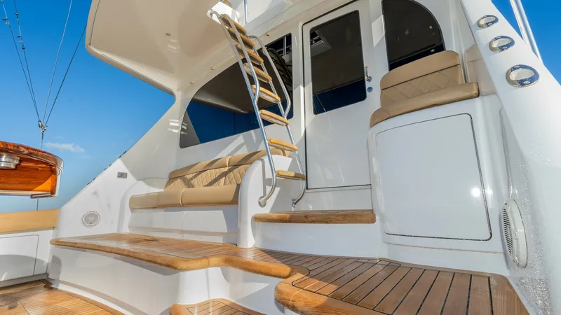 Slide: The Image of Aft Deck with Teak Steps This image showcases the elegant aft deck of the 2019 Viking 68 Enclosed Bridge, featuring beautifully crafted teak steps leading to the enclosed bridge. The seating area is adorned with plush, weather-resistant cushions, offering comfort and style. The s - 8738056