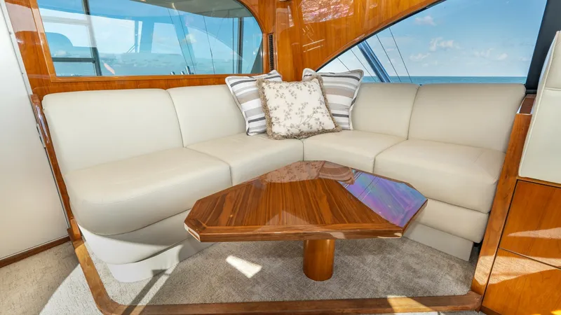 Slide: The Image of Elegant Salon Seating Area The salon of the 2019 Viking 68 Enclosed Bridge features a plush L-shaped sofa with cream leather upholstery, offering a luxurious space to relax. The high-gloss wooden coffee table complements the rich wood paneling and large windows provide stunning oce - 8738026