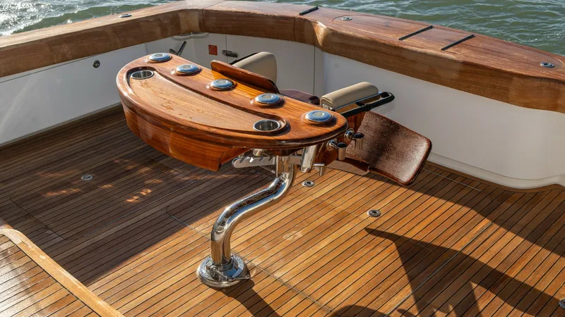 Slide: The Image of Teak Cockpit with Fighting Chair This image showcases the spacious teak cockpit of the 2019 Viking 68 Enclosed Bridge, featuring a beautifully crafted fighting chair. The rich wood finish and sleek stainless steel hardware highlight the high-quality materials used throughout. Designed fo - 8738059