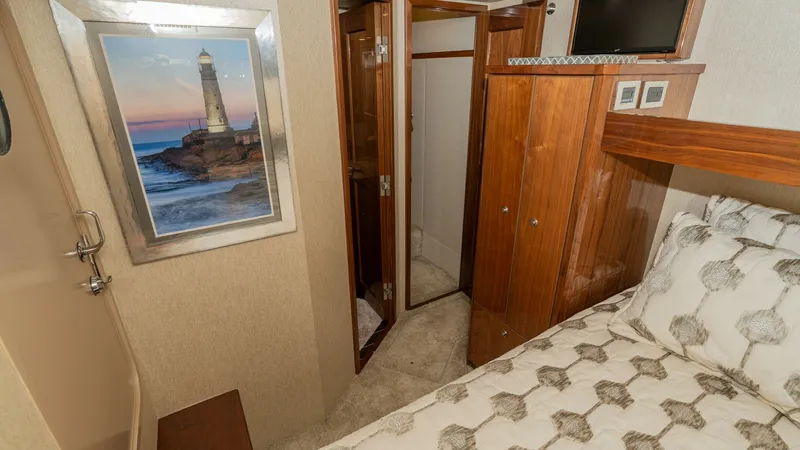 Slide: The Image of Guest Stateroom with Ensuite Access This cozy guest stateroom on the 2019 Viking 68 Enclosed Bridge features a plush bed with elegant patterned bedding. Warm wood cabinetry provides ample storage, complemented by tasteful artwork on the walls. The ensuite bathroom access enhances convenienc - 8738043