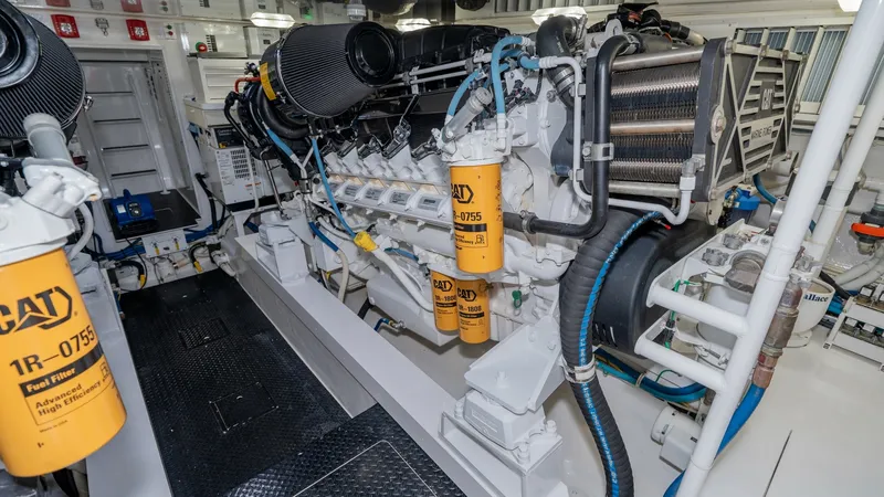 Slide: The Image of Engine Room with CAT Engines This engine room features powerful CAT engines, showcasing the heart of the 2019 Viking 68 Enclosed Bridge. The space is meticulously organized with clearly labeled filters and robust piping, ensuring optimal performance and easy maintenance. Bright light - 8738070