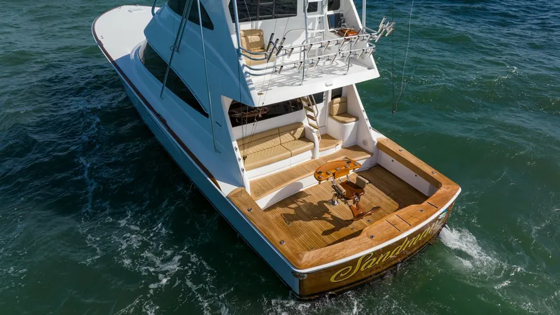 Slide: The Image of Aft Deck and Cockpit View This image showcases the spacious aft deck and cockpit of the 2019 Viking 68 Enclosed Bridge, 'Sandman'. The teak flooring adds a touch of elegance, complemented by the well-equipped fishing station perfect for avid anglers. The seating area offers comfor - 8738093