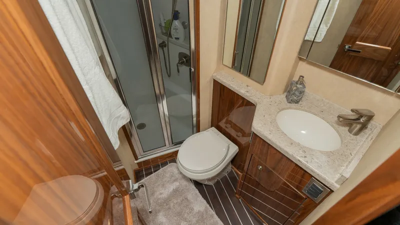 Slide: The Image of Elegant Ensuite Bathroom This sophisticated ensuite bathroom on the 2019 Viking 68 Enclosed Bridge features a sleek glass-enclosed shower and a modern vanity with a polished countertop. The warm wood finishes and contemporary fixtures create a luxurious and inviting space. Though - 8738031