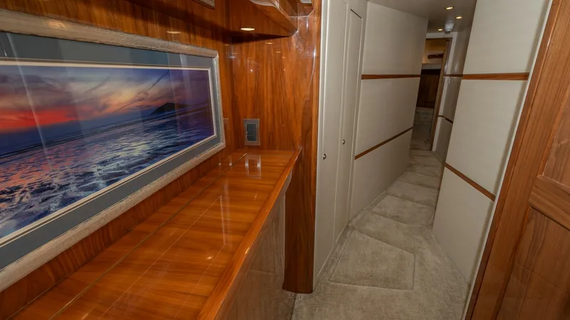 Slide: The Image of Elegant Hallway with Art Display This elegant hallway on the Viking 68 Enclosed Bridge showcases exquisite wood paneling and soft carpet flooring, creating a warm and inviting atmosphere. The space features integrated lighting that highlights a stunning piece of wall art, adding a touch - 8738038