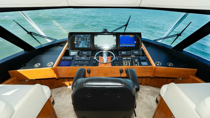 Slide: The Image of Commanding Helm Station The helm station of the 2019 Viking 68 Enclosed Bridge offers a commanding view with state-of-the-art navigation systems and a sleek, ergonomic design. The leather captain's chair is centrally positioned, surrounded by a comprehensive suite of advanced el - 8738022