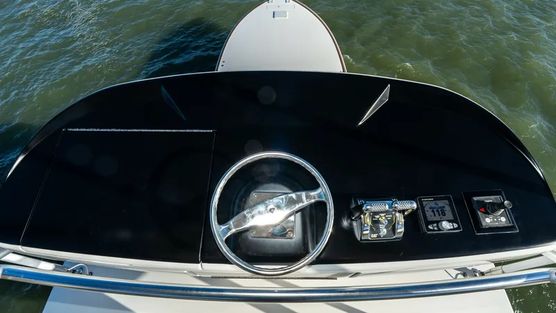 Slide: The Image of Flybridge Helm Station Overview This image showcases the helm station on the flybridge of the 2019 Viking 68 Enclosed Bridge. The sleek design features a polished steering wheel and state-of-the-art control panels, offering effortless navigation. The elevated position provides panoramic - 8738065