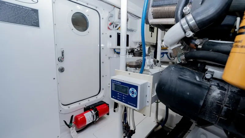 Slide: The Image of Engine Room with Access Door This image showcases the well-organized engine room of the 2019 Viking 68 Enclosed Bridge. The area features a sturdy access door with a porthole, ensuring easy entry and inspection. Visible are the high-quality control systems and equipment, designed for - 8738073
