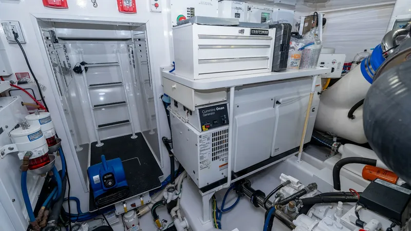 Slide: The Image of Engine Room with Equipment The engine room of the 2019 Viking 68 Enclosed Bridge, 'Sandman', showcases a well-organized layout with essential equipment. Prominent features include a Cummins Onan generator and a neatly arranged toolbox, ensuring efficient operation and maintenance. - 8738075