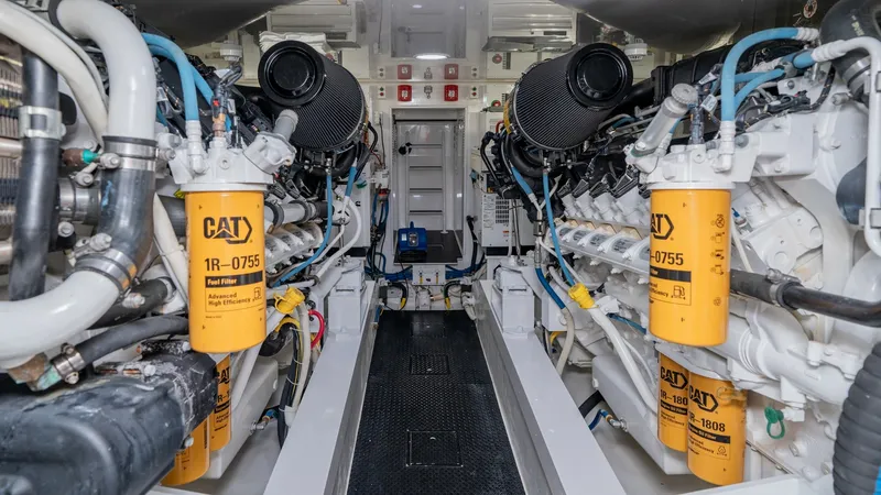 Slide: The Image of Engine Room with Twin CAT Engines The engine room of the 2019 Viking 68 Enclosed Bridge showcases twin powerful CAT engines, known for their reliability and performance. The space is meticulously organized with clearly labeled components and ample room for maintenance access. The bright l - 8738071