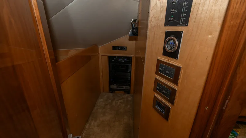 Slide: The Image of Control Panel and Electronics Area This image showcases the control panel and electronics area of the 2019 Viking 68 Enclosed Bridge. The space features a sleek, wood-paneled wall adorned with modern control interfaces, ensuring easy access to the vessel's systems. The carpeted flooring an - 8738046