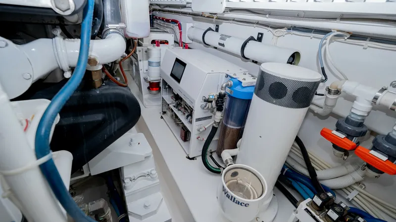 Slide: The Image of Engine Room with Advanced Systems The engine room of the 2019 Viking 68 Enclosed Bridge features state-of-the-art systems and meticulous organization. Visible are high-quality plumbing and electrical installations, ensuring optimal performance and reliability. The clean layout and modern - 8738072