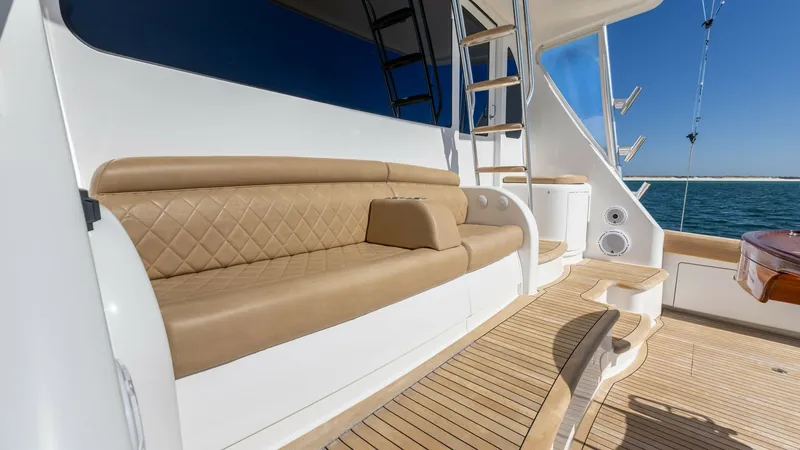 Slide: The Image of Aft Deck Seating Area This image showcases the elegant aft deck seating area of the 2019 Viking 68 Convertible, Gas Money. The space features plush tan upholstery with diamond stitching, offering a luxurious and comfortable spot for relaxation. The teak decking adds a touch of - 8679294