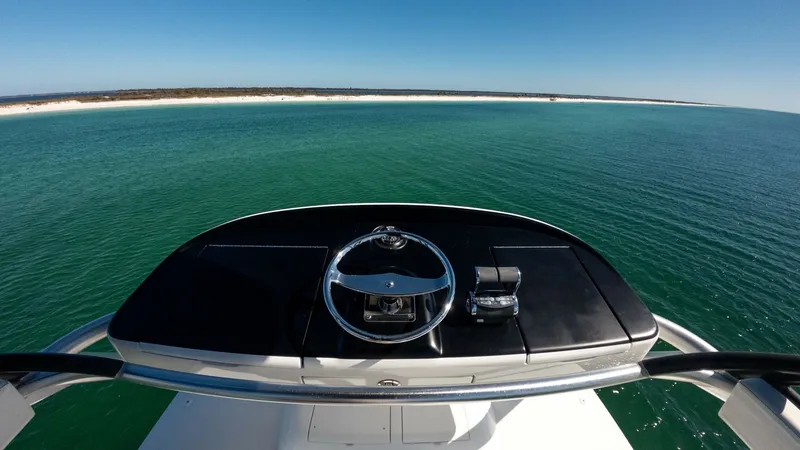 Slide: The Image of Flybridge Helm Station View The flybridge helm station of the 2019 Viking 68 Convertible offers a commanding view over the serene waters. Equipped with a sleek steering wheel and modern throttle controls, this area exemplifies functionality and style. The expansive horizon visible f - 8679290