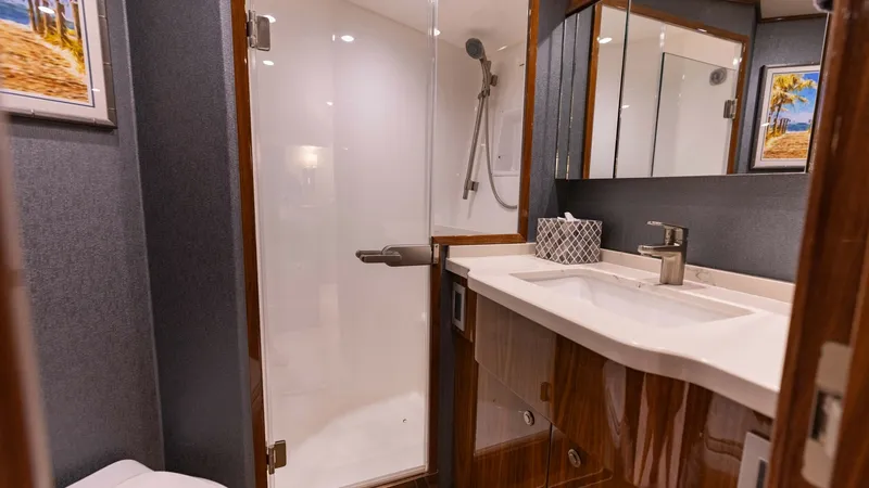 Slide: The Image of Elegantly Designed Ensuite Bathroom This luxurious ensuite bathroom aboard the 2019 Viking 68 Convertible features a spacious glass-enclosed shower and a sleek vanity with ample storage. The high-gloss wood finishes and contemporary fixtures create a sophisticated and inviting atmosphere, p - 8679272