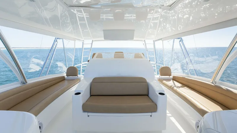 Slide: The Image of Flybridge Lounge Area The flybridge of the 2019 Viking 68 Convertible offers ample seating with plush, tan cushions and panoramic views of the open sea. The sleek white surfaces and modern design elements create an inviting atmosphere for relaxation and socializing. Enjoy the - 8679287
