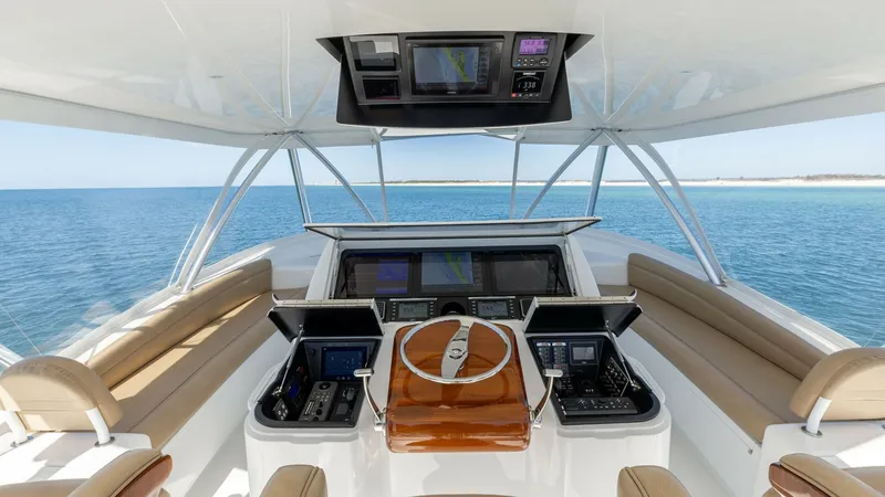 Slide: The Image of Flybridge Helm with Seating The flybridge helm of the 2019 Viking 68 Convertible 'Gas Money' offers a commanding view and state-of-the-art navigation systems. The sleek, polished wood steering wheel is flanked by advanced electronic displays and controls for precise handling. Comfor - 8679256