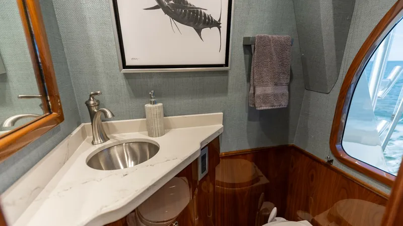 Slide: The Image of Elegant Yacht Bathroom This sophisticated bathroom on the 2019 Viking 68 Convertible features a sleek stainless steel sink set into a pristine marble countertop. The warm wood paneling adds a touch of luxury, complemented by the soft, ambient lighting. A large window offers a g - 8679263