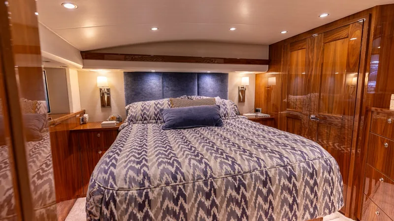 Slide: The Image of Master Stateroom with Luxurious Finish The master stateroom of the 2019 Viking 68 Convertible features a spacious layout with a plush, patterned bed at its center. Rich wood finishes and elegant cabinetry provide ample storage, while soft, ambient lighting creates a warm and inviting atmospher - 8679258