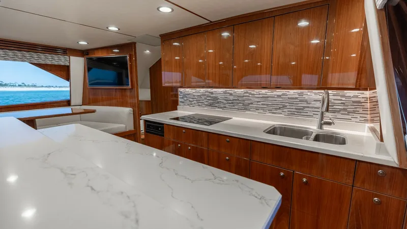 Slide: The Image of Galley with Marble Countertops This stylish galley on the Viking 68 Convertible features elegant marble countertops and rich wooden cabinetry, creating a luxurious yet functional space. The area is well-equipped with a modern stovetop, double sink, and ample storage, perfect for culina - 8679266