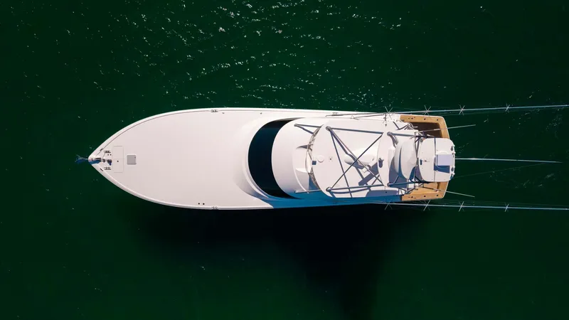 Slide: The Image of Aerial View of Flybridge and Deck This overhead shot of the 2019 Viking 68 Convertible showcases the sleek flybridge and expansive aft deck. The vessel's streamlined design is complemented by its advanced tower structure, ideal for spotting marine life or navigating open waters. The spaci - 8679306
