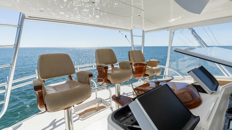 Slide: The Image of Flybridge with Helm Seating The flybridge of the 2019 Viking 68 Convertible, 'Gas Money', offers a commanding view with its ergonomic helm station. Featuring plush, adjustable captain's chairs with rich wooden accents, this area ensures both comfort and style for navigation. The ope - 8679286