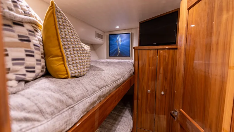 Slide: The Image of Guest Cabin with Upper Bunk This cozy guest cabin features a comfortable upper bunk adorned with plush pillows and soft bedding, ideal for restful nights at sea. The warm wood finishes and ambient lighting create an inviting atmosphere, while the built-in cabinetry provides ample st - 8679277