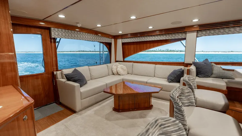 Slide: The Image of Spacious Salon with Panoramic Views This elegant salon aboard the 2019 Viking 68 Convertible features a luxurious L-shaped sofa, complemented by a stylish wooden coffee table. Large windows provide panoramic ocean views, enhancing the open and airy atmosphere. The high-quality finishes and - 8679261