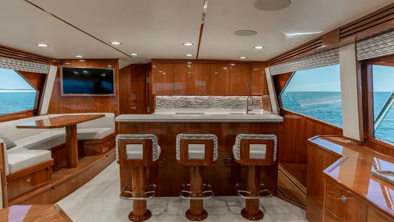 Slide: The Image of Spacious Galley and Dining Area This elegant galley and dining area on the 2019 Viking 68 Convertible features a sleek, modern design with high-gloss wood cabinetry and luxurious finishes. The galley is equipped with a stylish countertop and bar seating, perfect for entertaining guests. - 8679257