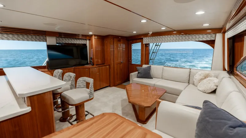 Slide: The Image of Spacious Salon with Ocean Views The salon of the 2019 Viking 68 Convertible 'Gas Money' offers an inviting and luxurious space with panoramic ocean views. It features a comfortable L-shaped sofa, a stylish wooden coffee table, and a state-of-the-art entertainment system. The open layout - 8679262
