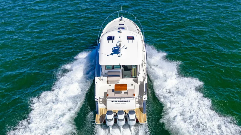 Slide: The Image of Aerial View of Aft Deck and Engines This aerial shot captures the sleek aft deck of the 2022 Back Cove 390, showcasing its powerful triple outboard engines slicing through the water. The spacious deck offers ample seating and relaxation areas, perfect for entertaining guests. The vessel's e - 8738170