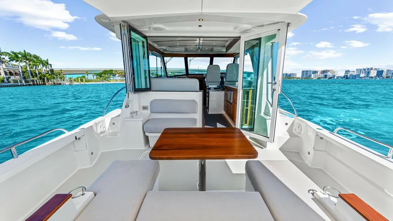 Slide: The Image of Spacious Aft Deck with Seating Area The aft deck of the 2022 Back Cove 390, 'Risk and Reward', features a comfortable seating area with plush cushions and a sleek wooden table, perfect for al fresco dining. The open layout and glass doors provide seamless access to the interior, enhancing t - 8738143