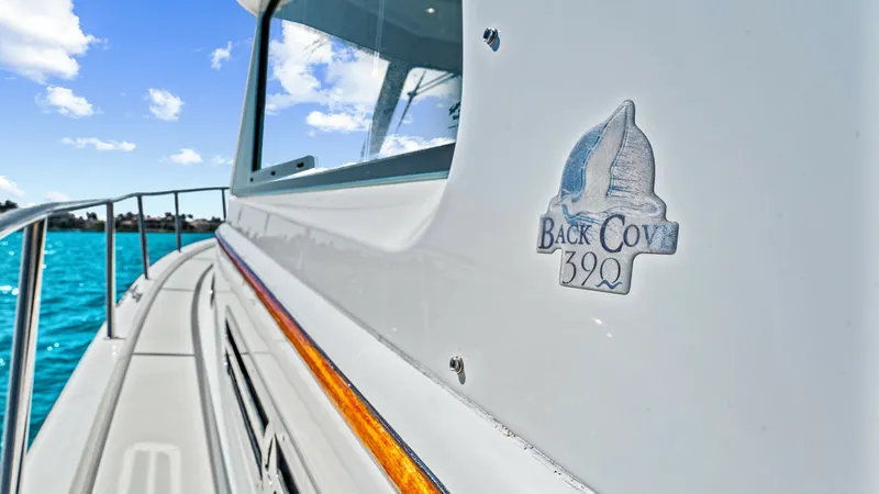 Slide: The Image of Side Deck and Branding Detail The image showcases the sleek side deck of the Back Cove 390, highlighting its smooth lines and polished finish. The vessel's branding is prominently displayed, reflecting its 2022 craftsmanship and modern design. The bright, clear skies and turquoise wat - 8738154