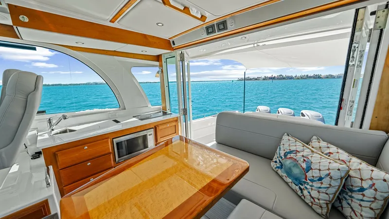 Slide: The Image of Spacious Aft Deck Lounge Area The aft deck of the 2022 Back Cove 390 features a luxurious seating area with plush cushions and a beautifully crafted wooden table, perfect for entertaining. Large sliding glass doors open to reveal stunning ocean views, seamlessly connecting the indoor - 8738126