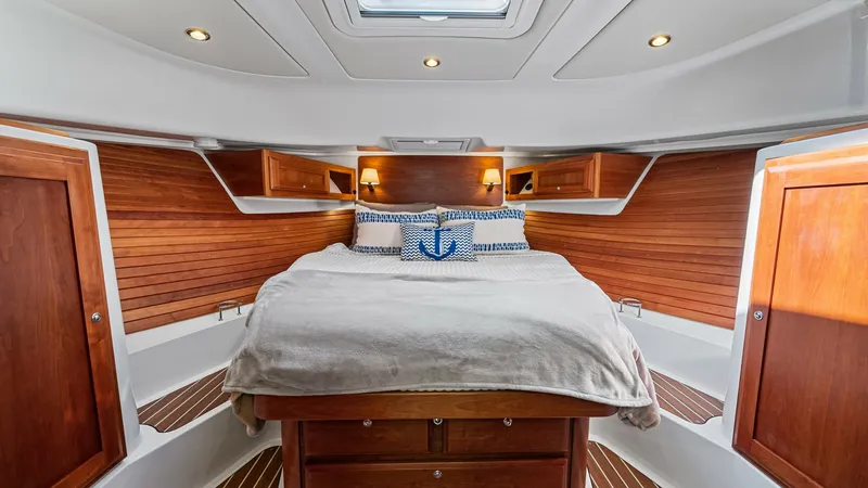 Slide: The Image of Forward Cabin with Queen Berth The forward cabin of the Back Cove 390 features a spacious queen berth, accented by rich wood paneling and ample storage. The overhead skylight and recessed lighting create a bright, inviting atmosphere. Elegant cabinetry and nautical-themed decor enhance - 8738137